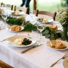 Un repas simple et champêtre, parfait pour une idée repas lendemain mariage. Des assiettes dressées avec purée, légumes verts et pain frais, entourées de verdure et de fleurs sauvages.
