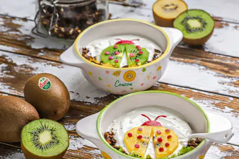 Recette kiwi trop mûr : yaourt et granola décorés d'une coccinelle en kiwi et fruits rouges. Parfait pour un petit-déjeuner ludique.