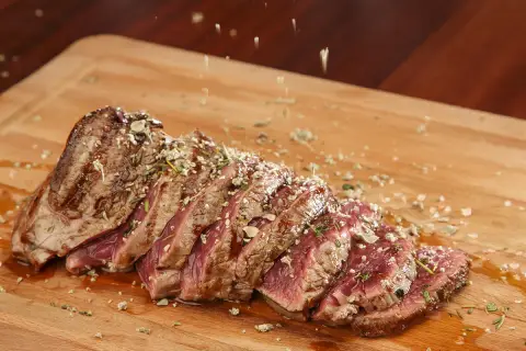 Un succulent côte de bœuf, tranché et parsemé d'herbes, prêt à être dégusté. Une croûte de sel subtile rehausse sa saveur.
