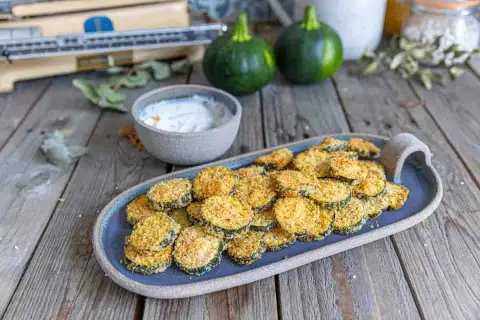 Galette de courgette parmesan au four, croustillante et dorée, servie avec une sauce crémeuse. Un délice simple et savoureux.