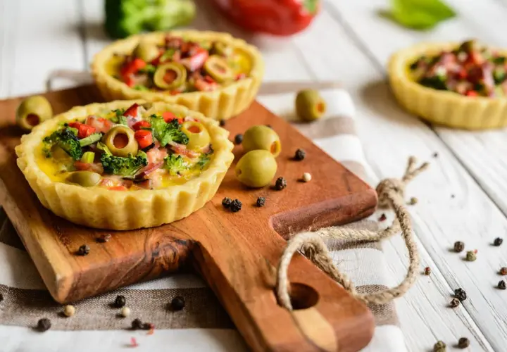 Mini quiches colorées sur fond de bois blanc, une idée pour que faire avec un reste de pâte brisée.