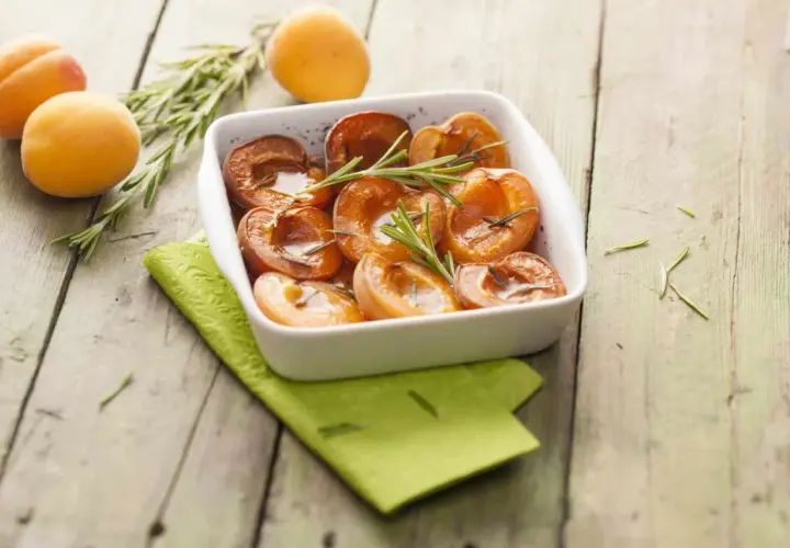 Abricots rôtis au four, tendres et caramélisés, garnis de romarin frais. Un délice simple et parfumé.