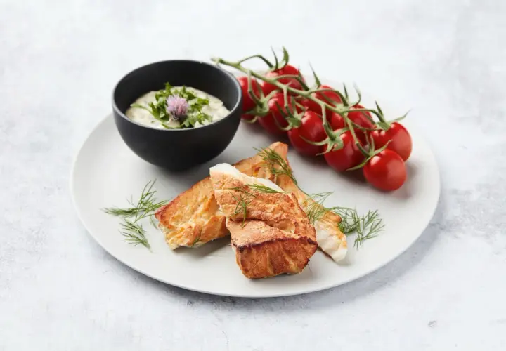 Délicieux cabillaud au barbecue, servi avec une sauce crémeuse, des tomates cerises et de l'aneth frais.