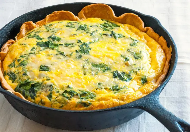 Quiche aux épinards dans une poêle en fonte, parfaite pour une recette jaune d'oeuf.
