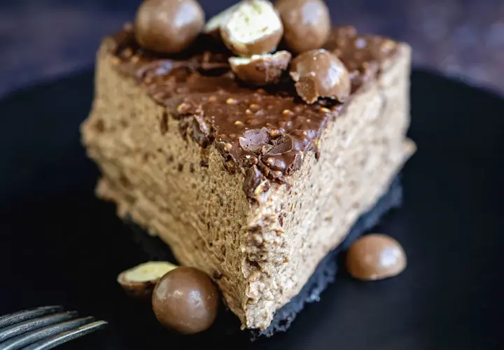 Une part de gâteau au chocolat aérien, garnie de boules Malteser croquantes et d'un glaçage au chocolat.