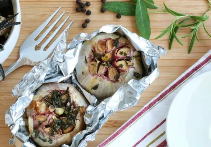 Deux têtes d'ail au barbecue, enveloppées dans du papier d'aluminium, avec des herbes et des épices.