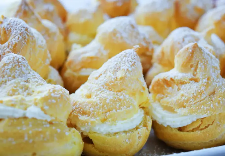 Choux garnis de crème, saupoudrés de sucre glace. Pour qu'ils restent gonflés, il faut bien cuire la pâte à choux et ne pas ouvrir le four trop tôt.