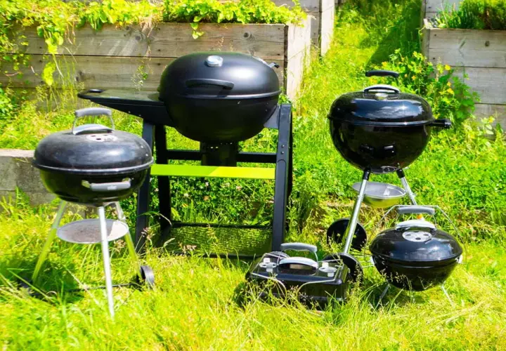 Plusieurs barbecues, certains à charbon, d'autres à bois, sont prêts pour un festin estival dans l'herbe verte.