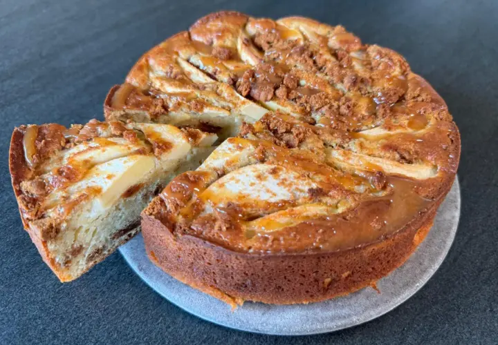 Gâteau pomme spéculoos, une part coupée révèle la texture moelleuse et les morceaux de spéculoos. Un délice gourmand.