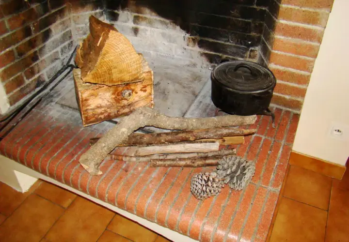 Prêt à allumer le feu avec des pommes de pin, du petit bois et des bûches. Une marmite en fonte est posée près du foyer.