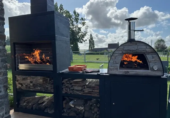 Un barbecue et un four à pizza en pierre, tous deux allumés, prêts pour un repas. Idéal pour savoir comment faire un barbecue sans charbon, avec du bois stocké en dessous.