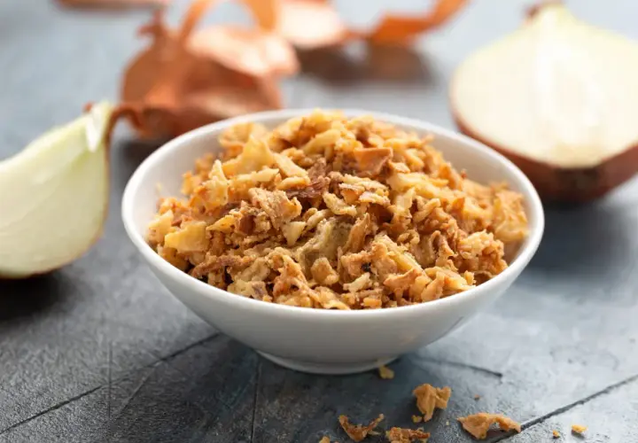 Un bol de oignon crispy doré et croustillant, entouré d'oignons frais. Parfait pour garnir vos plats.