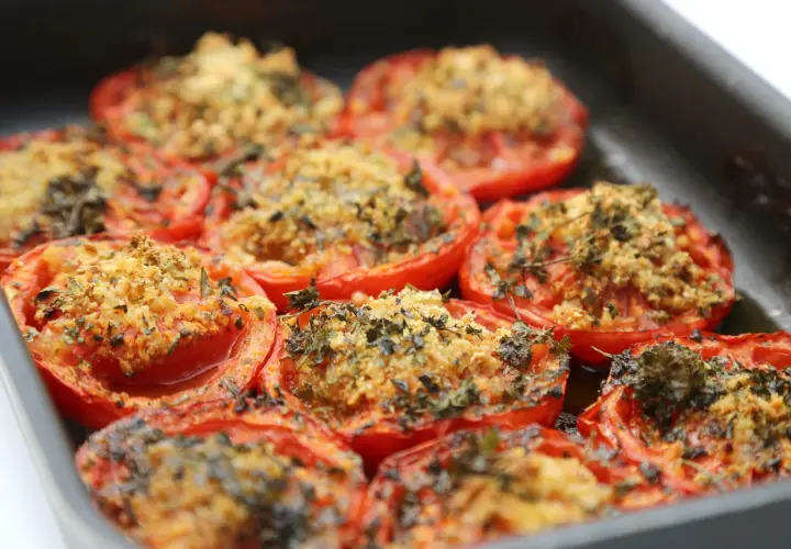 Tomates au barbecue, coupées en deux et garnies d'une chapelure dorée et d'herbes aromatiques, prêtes à être dégustées.