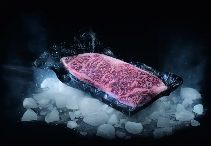 Un beau morceau de viande de bœuf marbré, emballé sous vide, posé sur de la glace pilée. Le processus pour décongeler viande est sur le point de commencer.