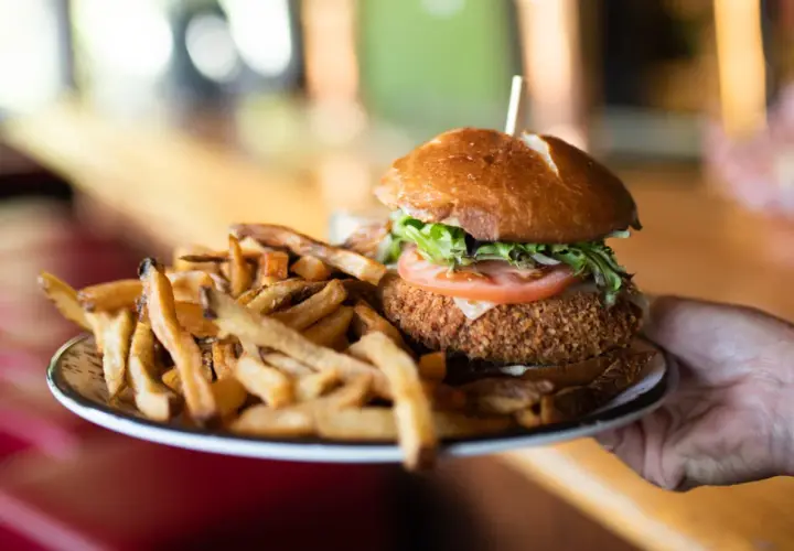 Un délicieux burger montagnard, croustillant et garni, servi avec une généreuse portion de frites dorées.