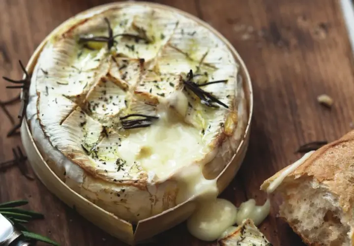 Un camembert au barbecue, fondant et parfumé au romarin, prêt à être dégusté avec une baguette croustillante.