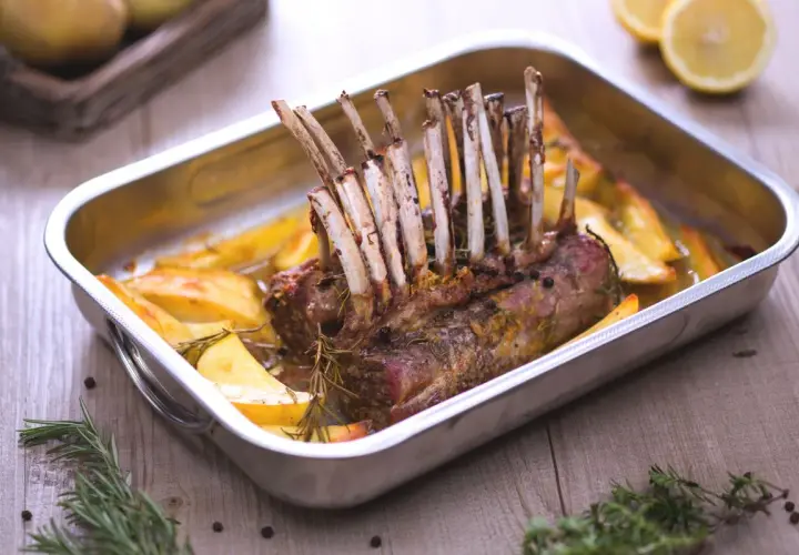 Un délicieux côte d'agneau rôti au four, accompagné de pommes de terre dorées et de romarin frais. Un plat savoureux prêt à être dégusté.