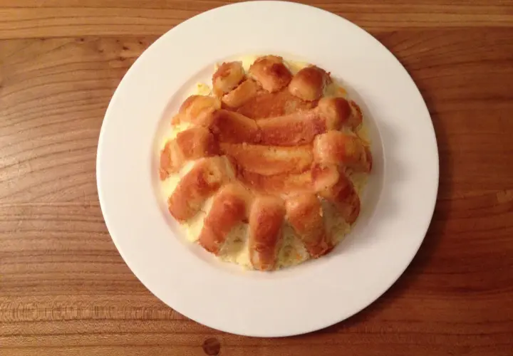 Charlotte à l'orange, un dessert doré et moelleux, servi sur une assiette blanche.