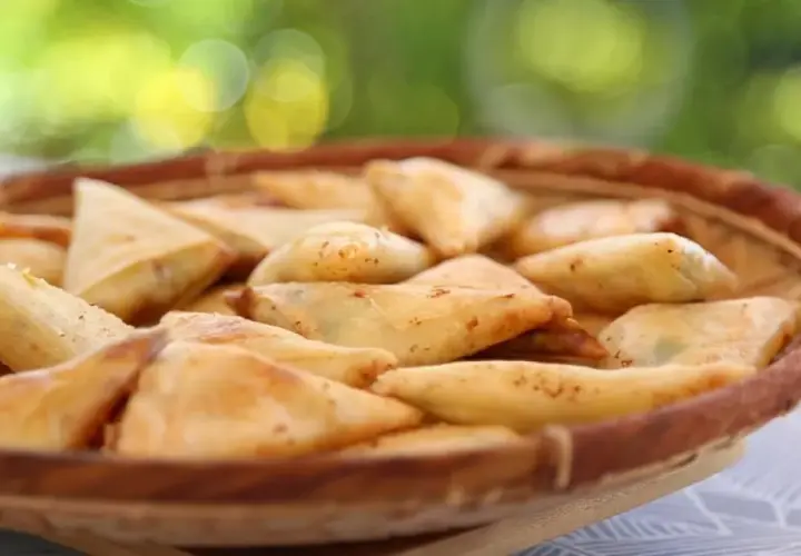 Un panier rempli de samoussas dorés, garniture pomme de terre fromage. Parfait pour un apéritif gourmand en extérieur.
