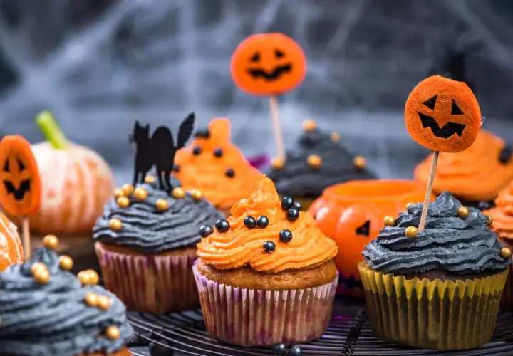 Des muffins d'Halloween effrayants, parfaits pour une recette facile. Glaçage orange et gris, décorés de citrouilles et d'un chat noir.