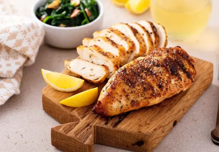 Poulet grillé, tranché, avec quartiers de citron, épinards et un verre de jus. Un plat savoureux, même s'il est resté hors du frigo 24h.