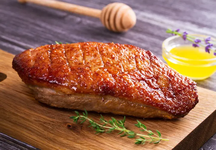 Magret de canard grillé à la perfection, prêt pour la cuisson barbecue gaz. Servi avec une sauce dorée et des herbes fraîches.