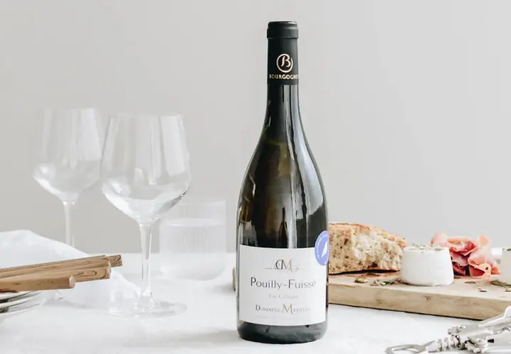 Bouteille de Pouilly-Fuissé, deux verres à vin, pain, fromage de chèvre et jambon. Parfait pour une liste boisson mariage.