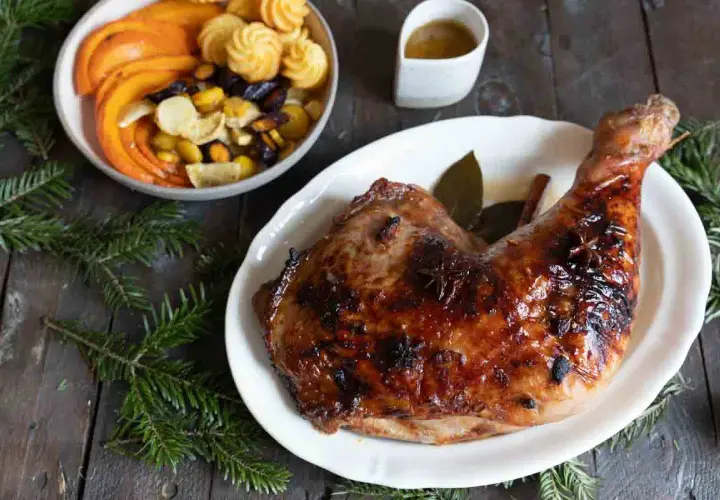 Une cuisse de dinde rôtie, brillante et savoureuse, parfaite pour une recette cuisse de dinde originale. Accompagnée de légumes et de petites bouchées.