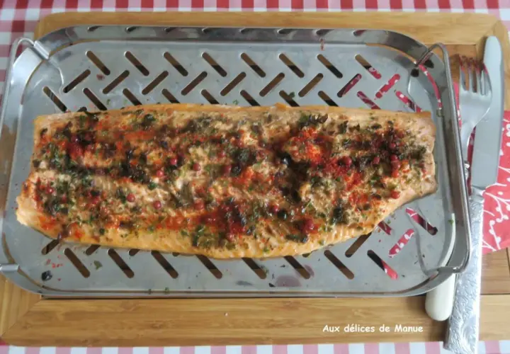 Filet de truite au four, parsemé d'herbes et de baies roses, prêt à être dégusté.