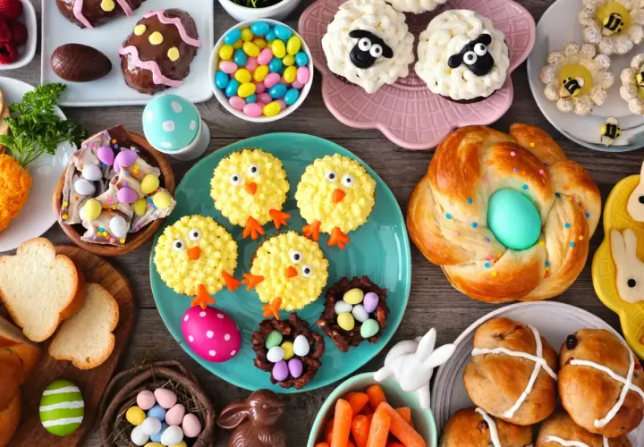 Table garnie de douceurs pascales : cupcakes moutons, poulets, biscuits abeilles, pains tressés, chocolats et bonbons. Parfaites recettes rigolotes pour Pâques !