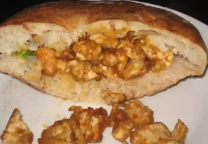 Un pain garni de morceaux de poulet épicés, prêt à déguster. Une recette kebab maison facile pour un repas savoureux.