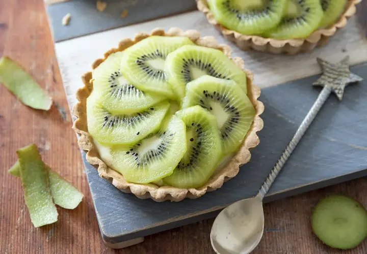 Délicieux dessert kiwi, une tartelette garnie de crème et de fines rondelles de kiwi, prête à être dégustée.