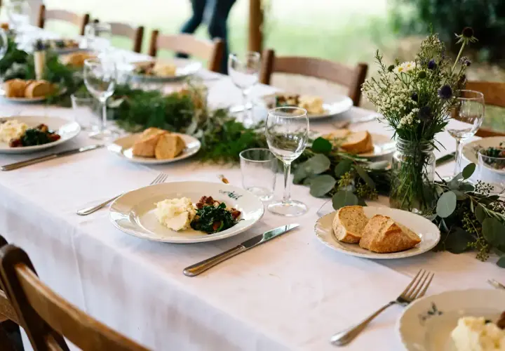 Un repas simple et champêtre, parfait pour une idée repas lendemain mariage. Des assiettes dressées avec purée, légumes verts et pain frais, entourées de verdure et de fleurs sauvages.