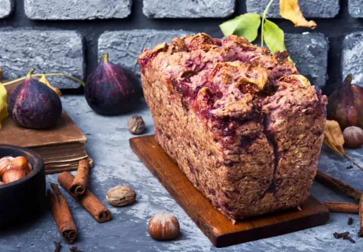 Gâteau rustique aux figues et noix, garni de fruits frais, de cannelle et de noisettes.