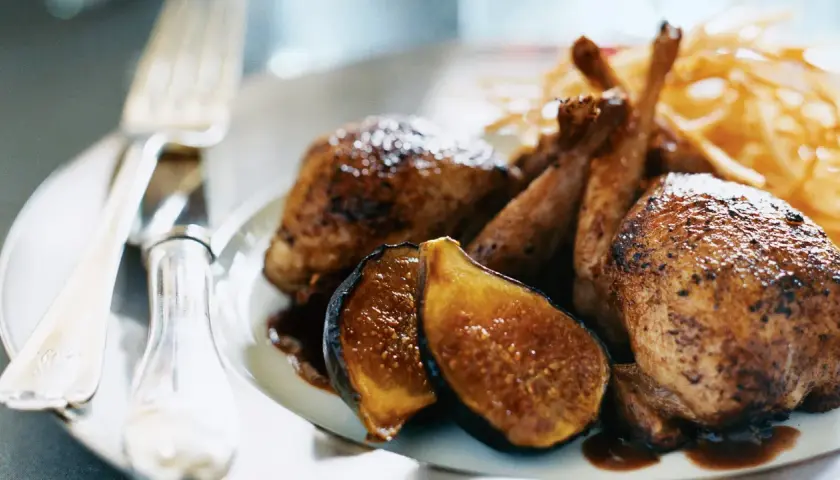 Délicieuse caille au four, servie avec des figues caramélisées et des frites croustillantes. Un plat savoureux prêt à être dégusté.