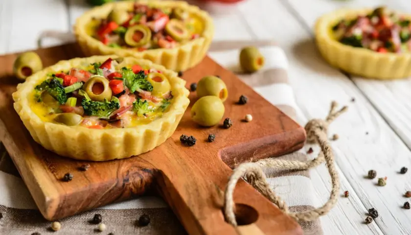 Mini quiches colorées sur fond de bois blanc, une idée pour que faire avec un reste de pâte brisée.