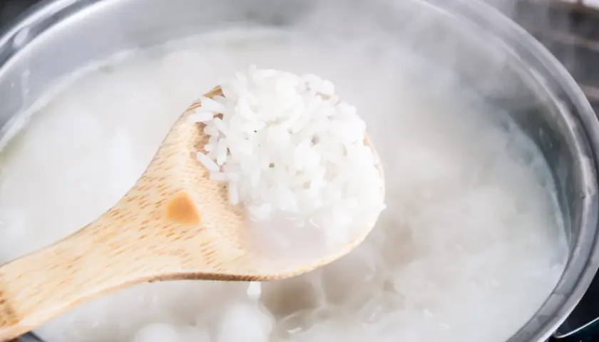 Une cuillère en bois sort du riz trop cuit bouillant dans une casserole. Que faire ?