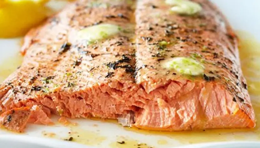 Un pavé de saumon barbecue, cuit à la perfection, avec des éclats de beurre fondant et des herbes.