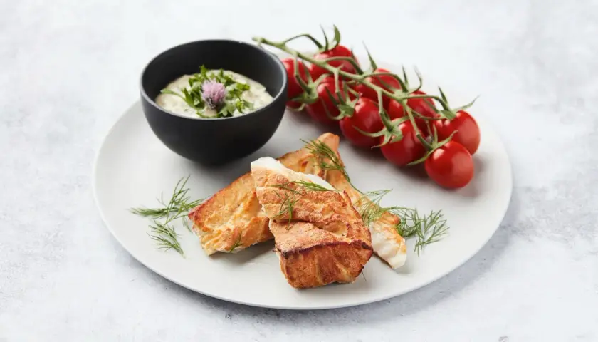 Délicieux cabillaud au barbecue, servi avec une sauce crémeuse, des tomates cerises et de l'aneth frais.