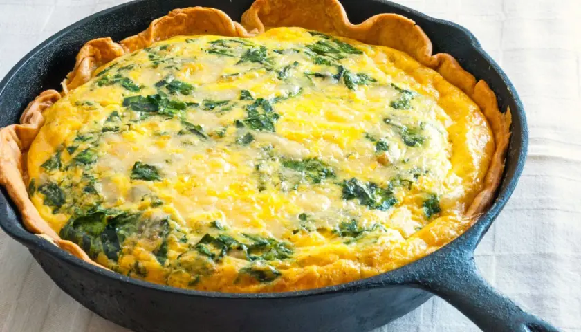 Quiche aux épinards dans une poêle en fonte, parfaite pour une recette jaune d'oeuf.