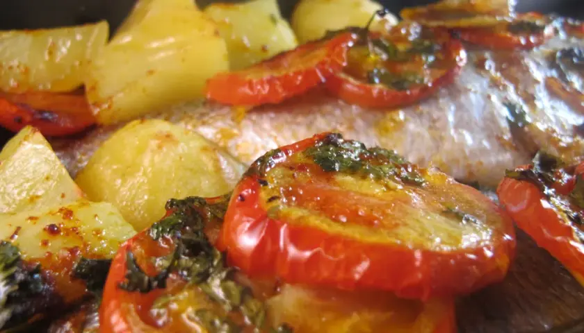 Dorade au four portugaise avec pommes de terre et tomates rôties, un plat savoureux et coloré.