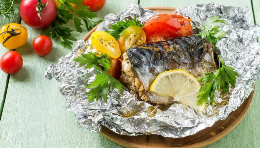 Poisson cuit dans l'aluminium, servi avec des tomates et du persil. Un délice simple et savoureux.