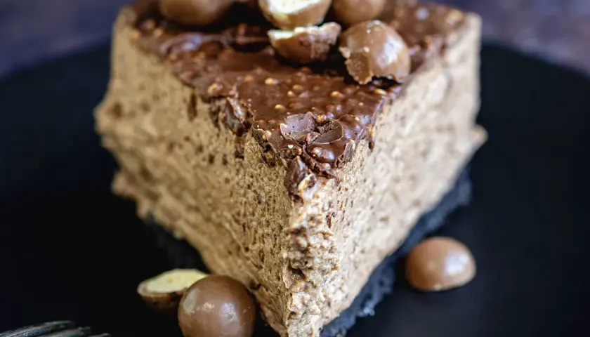 Une part de gâteau au chocolat aérien, garnie de boules Malteser croquantes et d'un glaçage au chocolat.