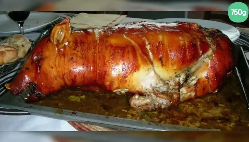 Un magnifique cochon de lait farci, rôti à la perfection, avec une peau dorée et croustillante, prêt à être dégusté.