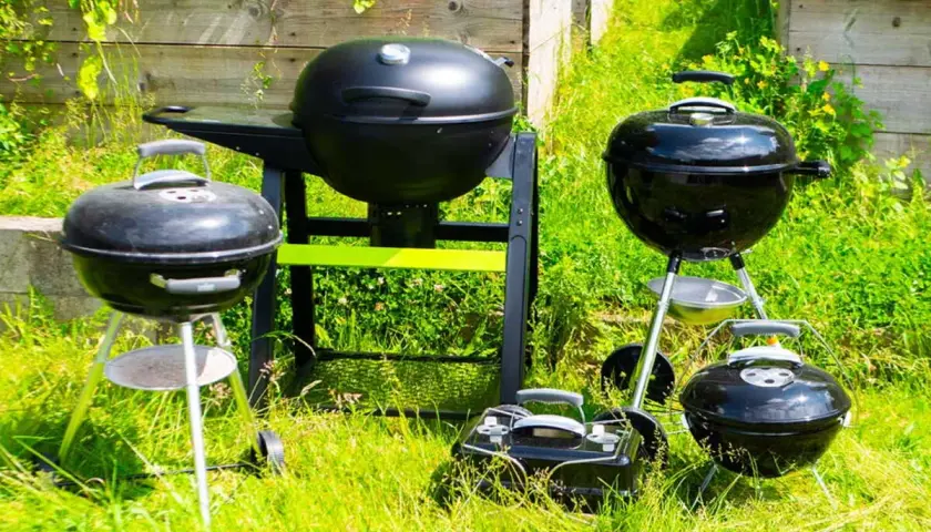 Plusieurs barbecues, certains à charbon, d'autres à bois, sont prêts pour un festin estival dans l'herbe verte.