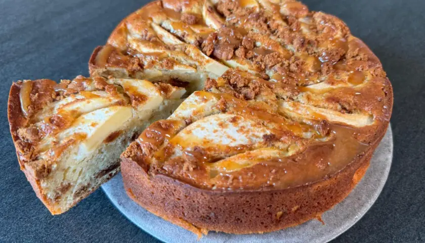 Gâteau pomme spéculoos, une part coupée révèle la texture moelleuse et les morceaux de spéculoos. Un délice gourmand.