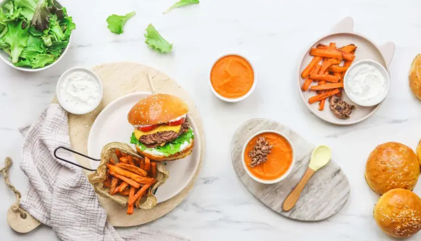 Un délicieux burger enfant avec frites de patate douce, purée de carottes et salade verte. Un repas complet et appétissant pour les petits gourmands.