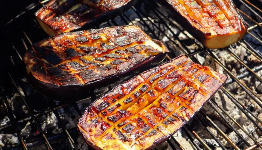 Aubergines coupées en deux, grillées au barbecue, avec des marques de cuisson caramélisées et une chair tendre.