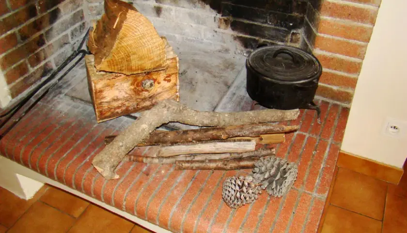 Prêt à allumer le feu avec des pommes de pin, du petit bois et des bûches. Une marmite en fonte est posée près du foyer.