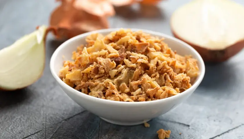 Un bol de oignon crispy doré et croustillant, entouré d'oignons frais. Parfait pour garnir vos plats.